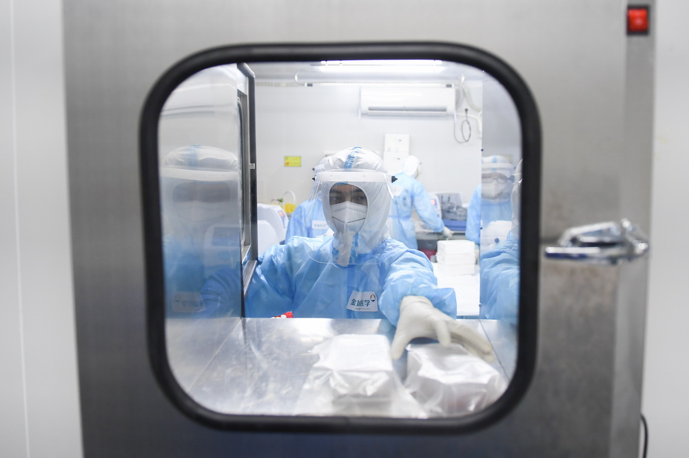 6月26日凌晨，检验人员从实验室传递窗内拿取反应试剂。