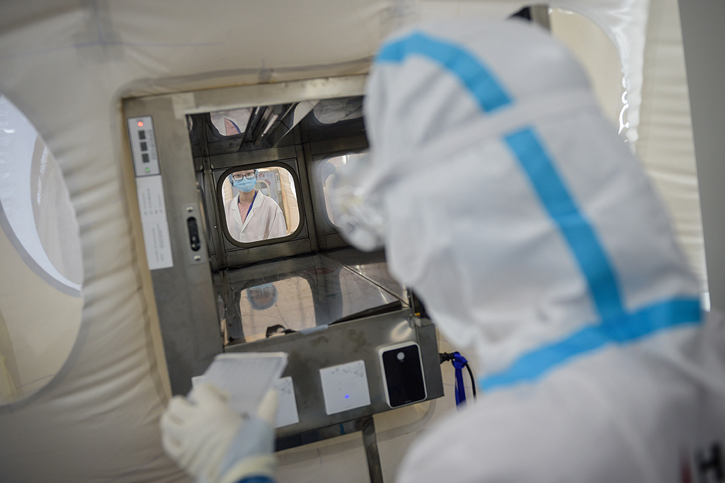 7月1日，在提取实验室内，实验人员（右）通过传递通道将物品转移到扩增实验室。新华社记者彭子洋摄