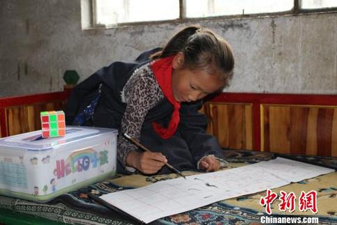 图为11岁藏族女孩青梅拉忠正在用“HELLO小孩”爱心套餐中的毛笔字帖临摹。　谢婉婉 摄